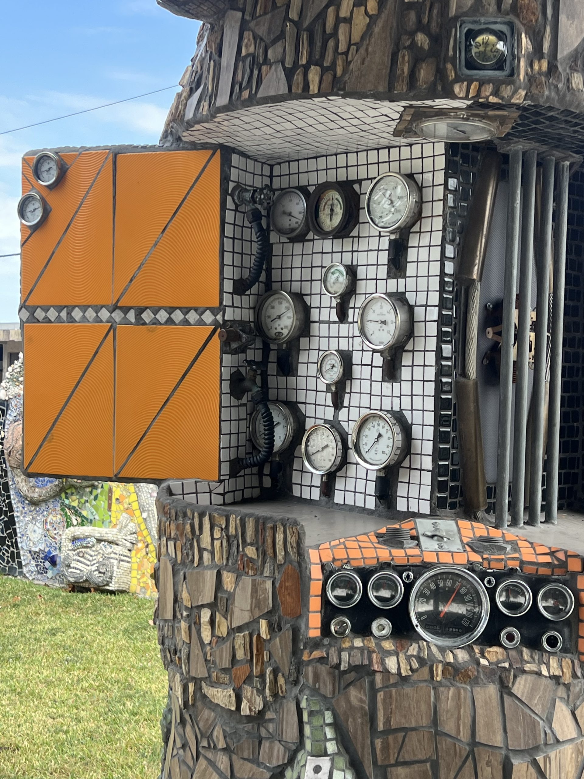 The mosaic work features about a dozen analog watches set in a box attached to a structure.