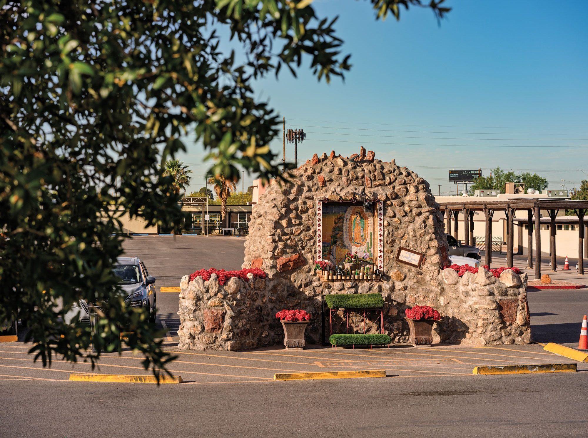 A shrine honoring the Lady of Guadalupe made of cobblestones stands in a parking lot.