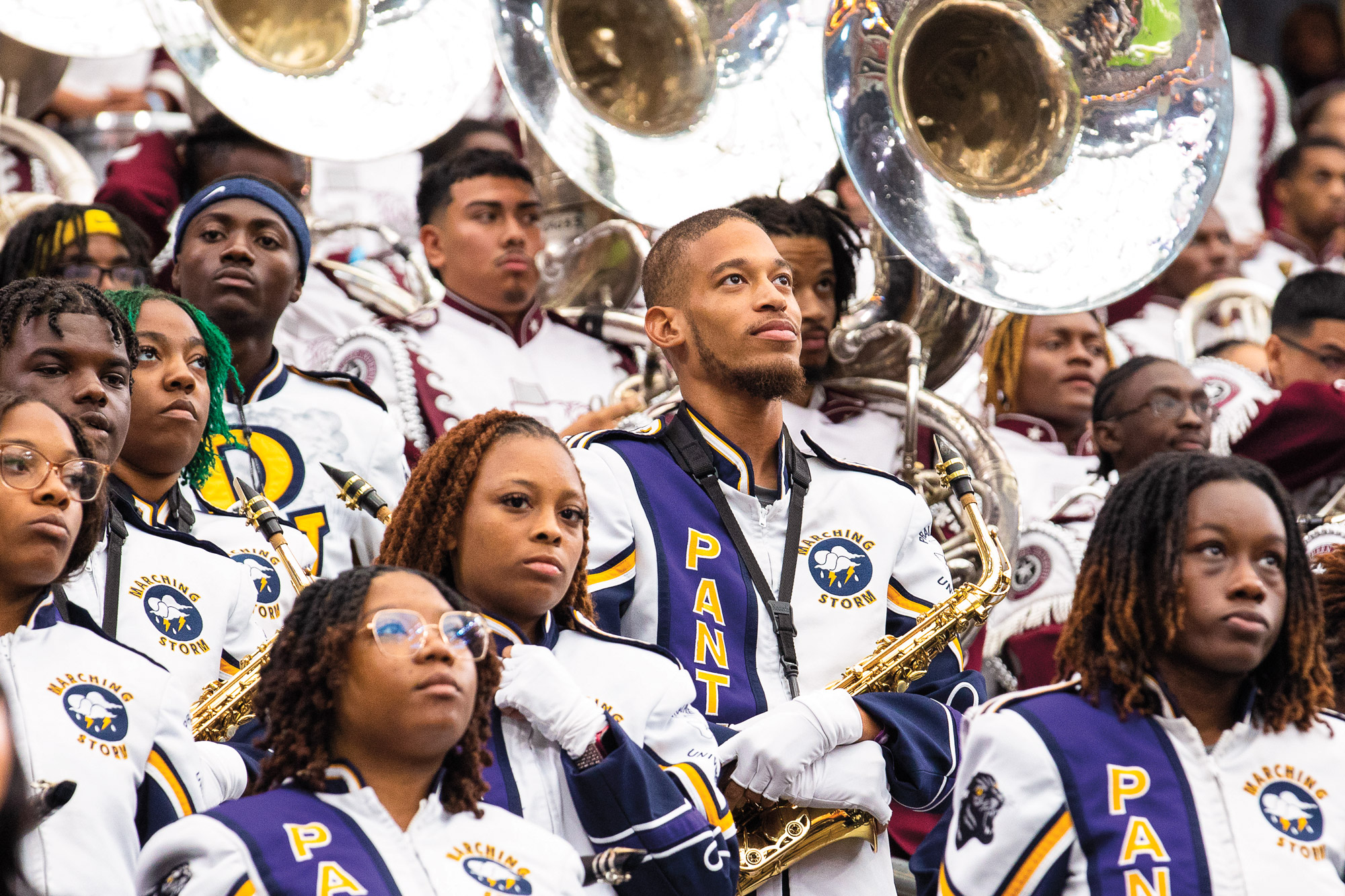 Horn players await the start of their performance in white and purple uniforms
