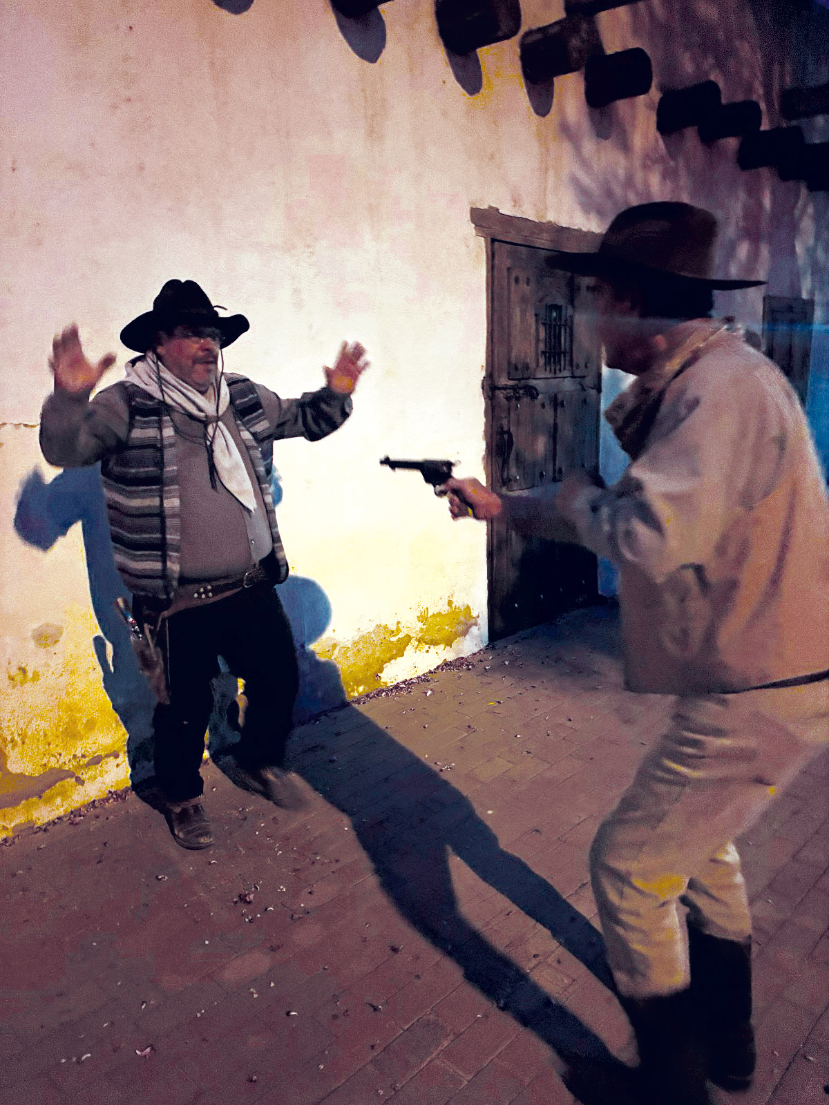 A reenactment of a man holding a gun pointed at another man who has his arms outstretched