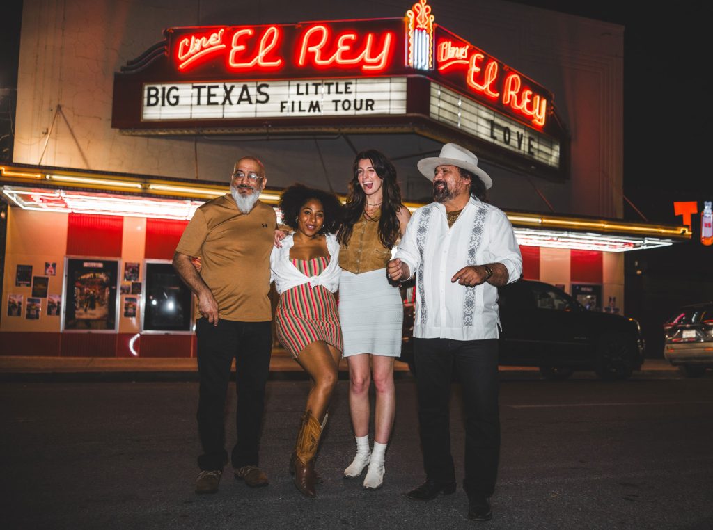 Four people stand in front of the lit-up neon marquee of Cine El Rey. The marquee reads Big Texas in big letters, Little Film Tour in small letters.