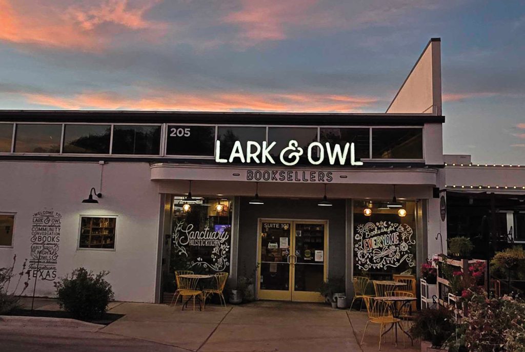 A building with colorful writing on its windows and a sign that reads Lark & Owl Booksellers