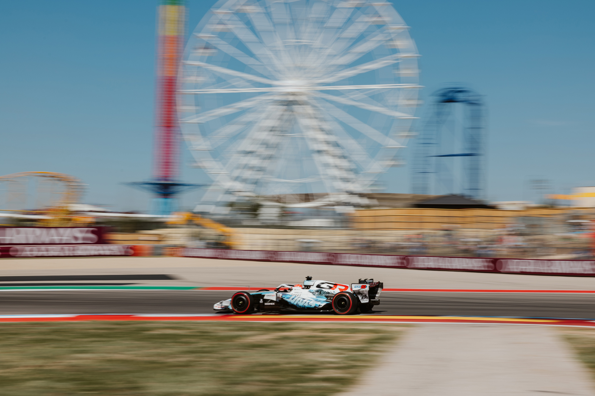 A race car on a track in front of a ferris wheel in the background