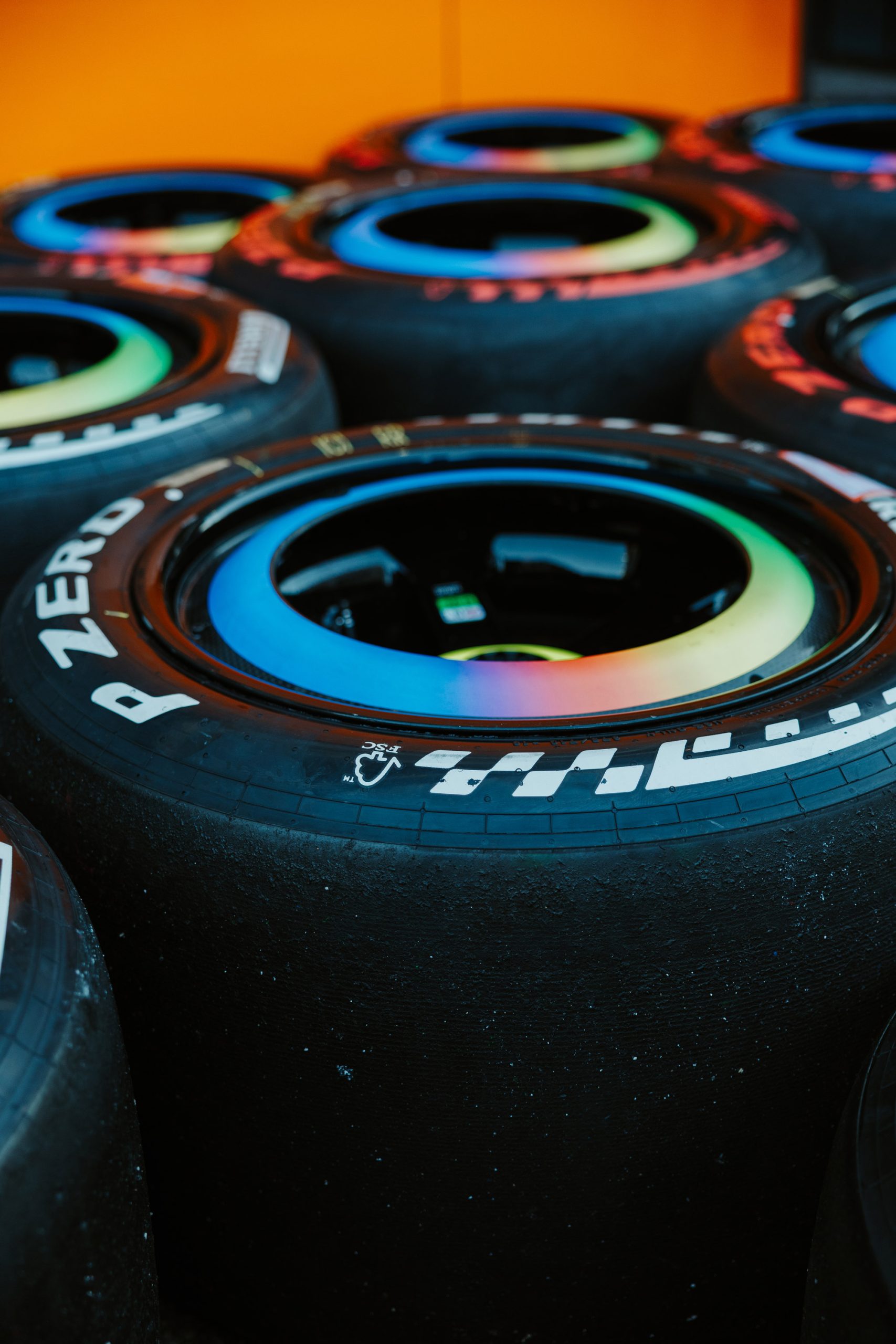 Used race car tires piled next to each other with colorful rainbow rims