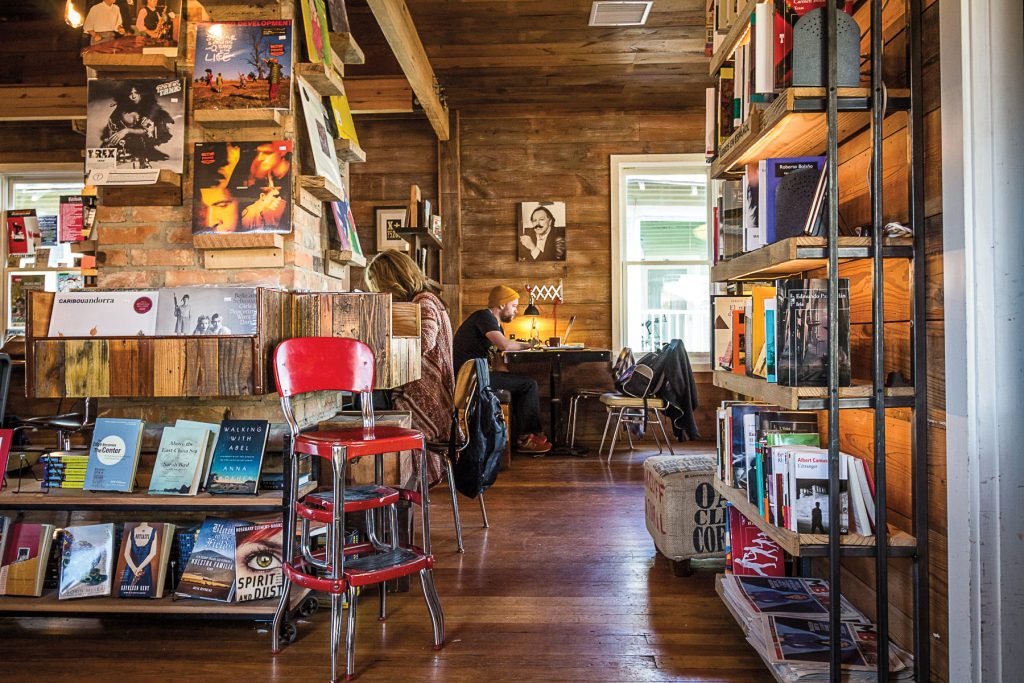 Two people sitting at different tables in a bookstore that also sells vinyl records